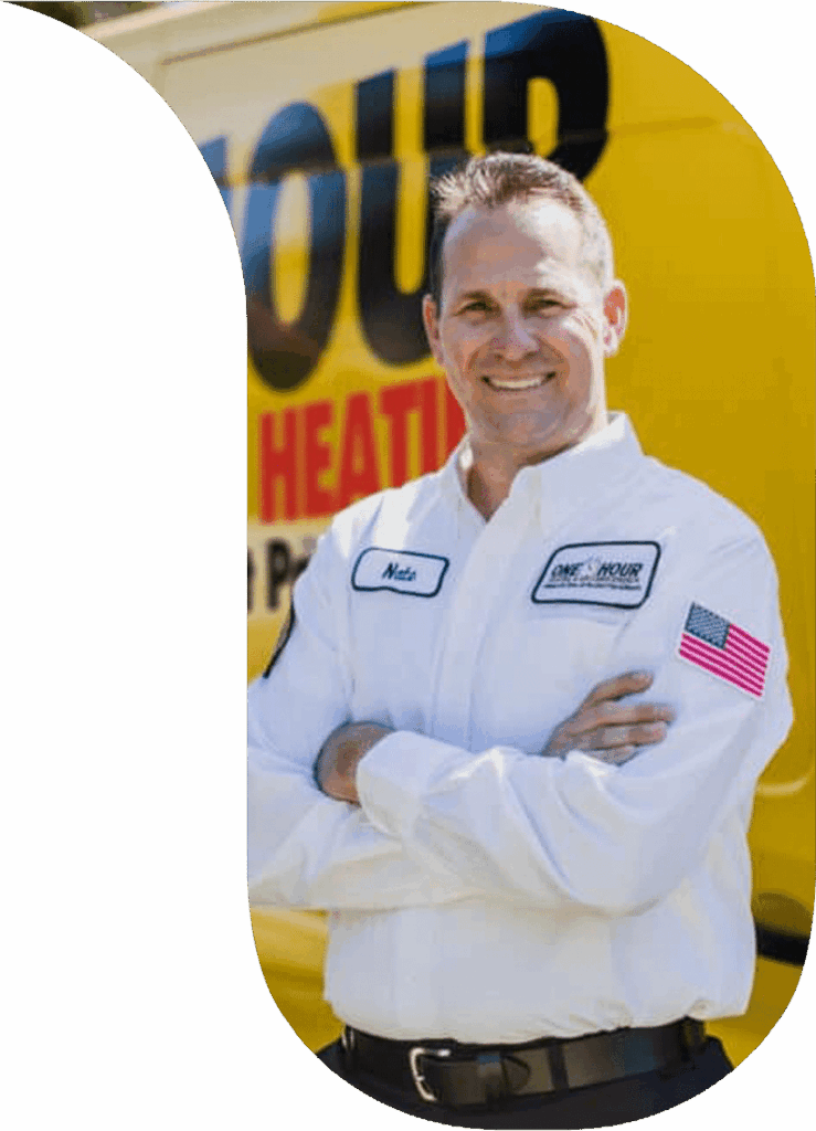 “Smiling service technician in a white branded uniform with arms crossed, standing in front of a yellow heating and air service van