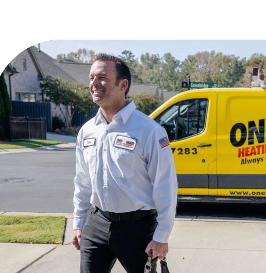 Uniformed home service technician walking toward a customer’s home with a company service truck parked nearby.​