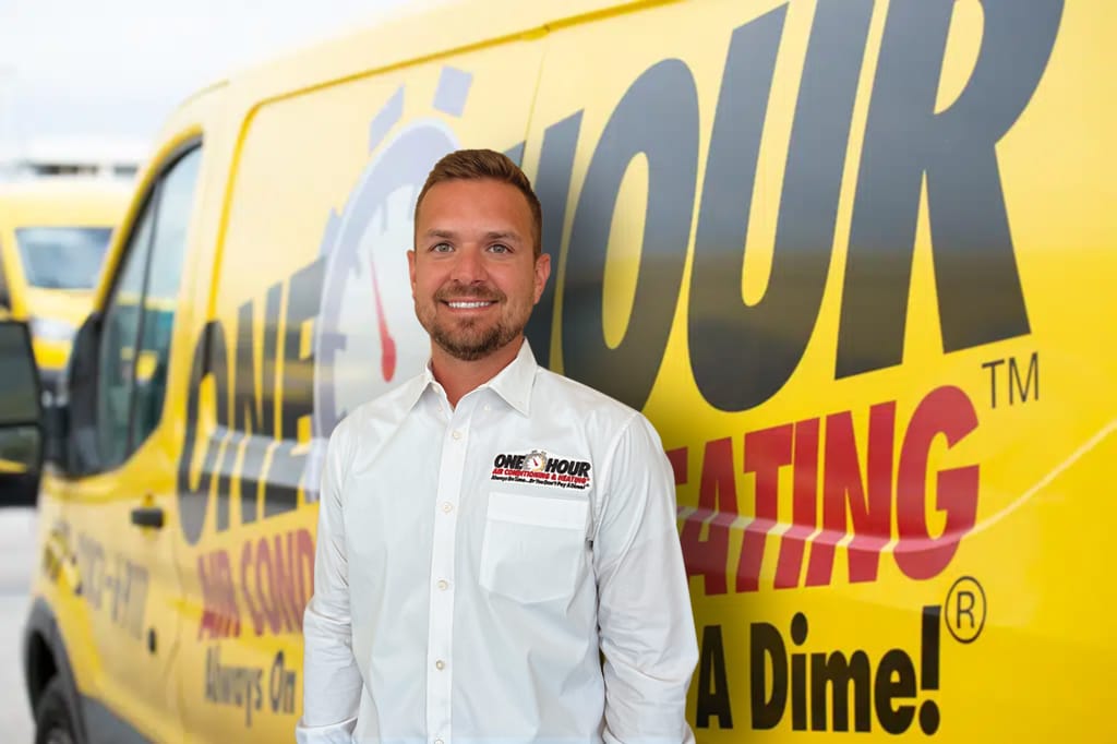 One Hour Air Conditioning & Heating technician standing in front of a branded service van, representing reliable HVAC service