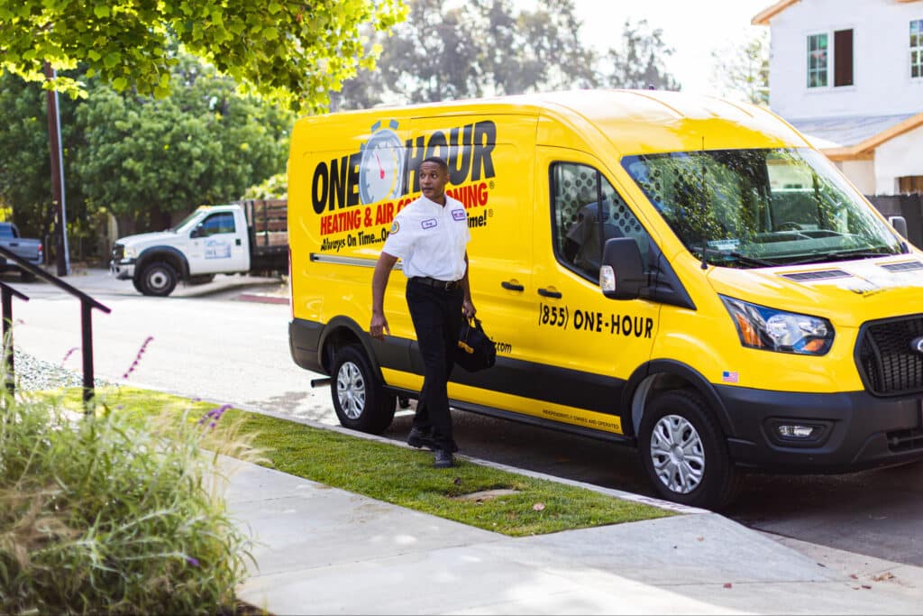 One Hour Air Conditioning & Heating technician arriving at a customer’s home in a branded service van